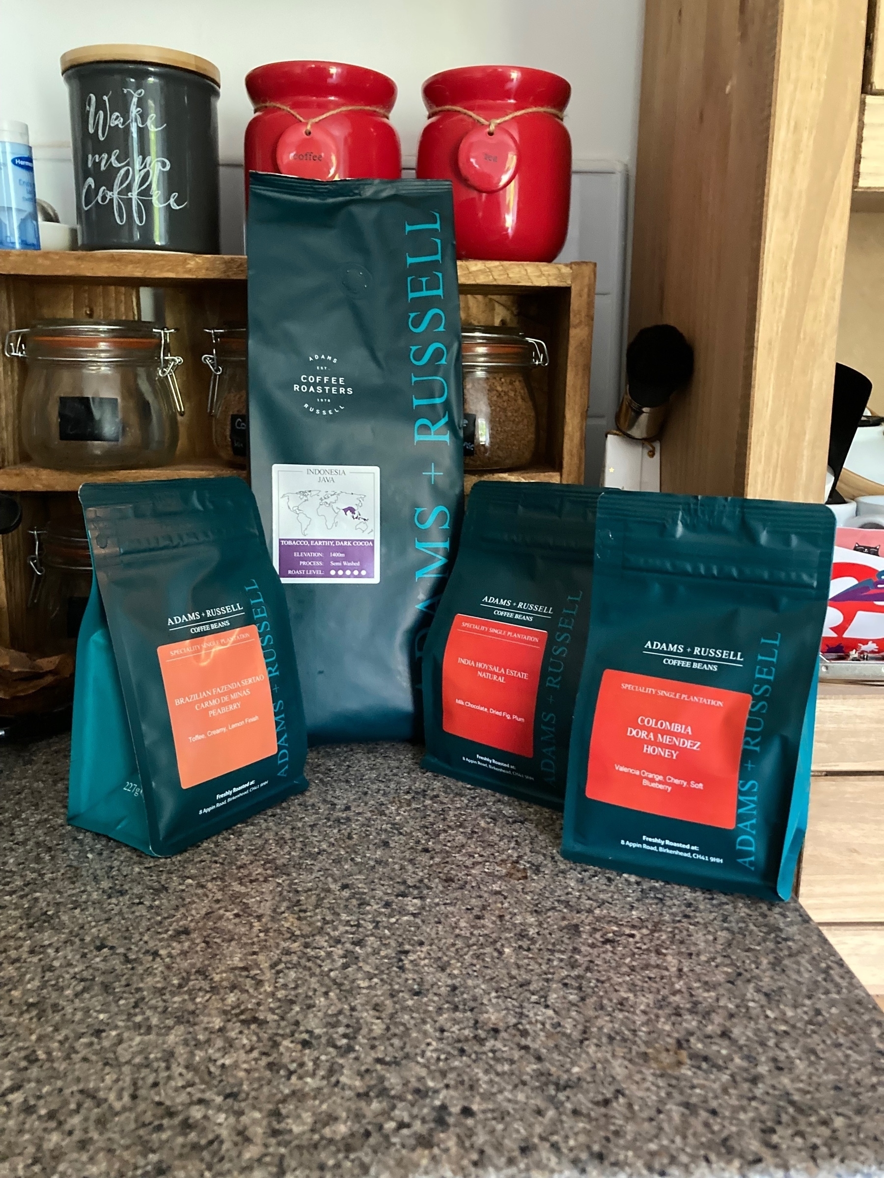 Four new bags of coffee, on top of a kitchen counter.